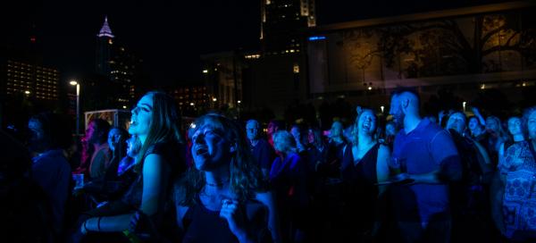 Red Hat Amphitheater attendees sing along during an evening concert