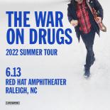 Cover photo with a man walking in snow with a coffee mug in one hand and a guitar in the other. Text reads: THE WAR ON DRUGS 2022 Summer Tour.