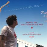 A photo of Dominic Fike wearing a white shirt staring up at the sky.