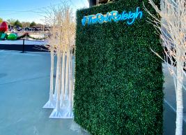 a photo of a green wall with the words #TheRinkRaleigh written on it in blue text