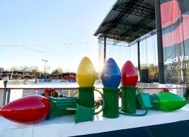 a photo of large light bulb ornaments outside of the ice rink